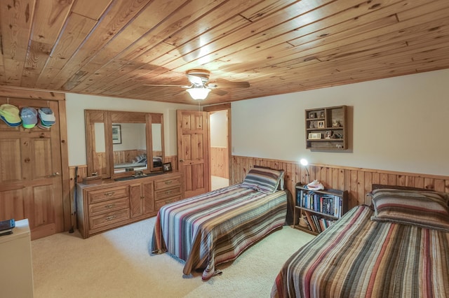 bedroom featuring light colored carpet, wood ceiling, wooden walls, and ceiling fan