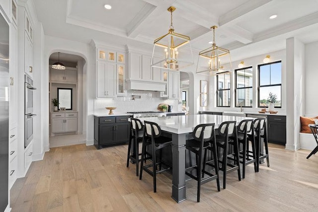 kitchen with a center island, decorative light fixtures, white cabinetry, light hardwood / wood-style floors, and tasteful backsplash