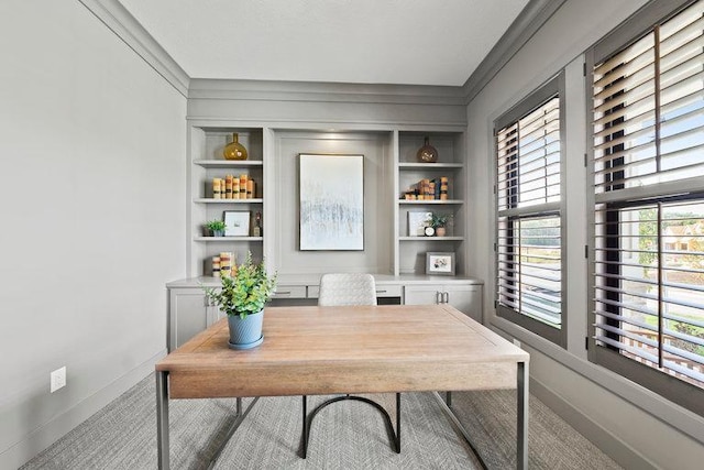 carpeted office space featuring crown molding and built in shelves