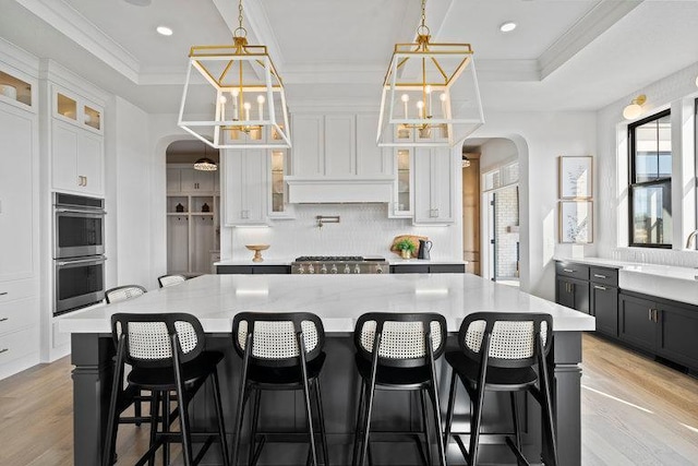 kitchen with a large island, a kitchen breakfast bar, white cabinets, and pendant lighting