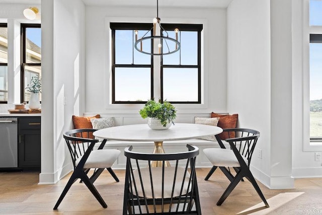 dining space featuring breakfast area, a healthy amount of sunlight, light hardwood / wood-style flooring, and an inviting chandelier