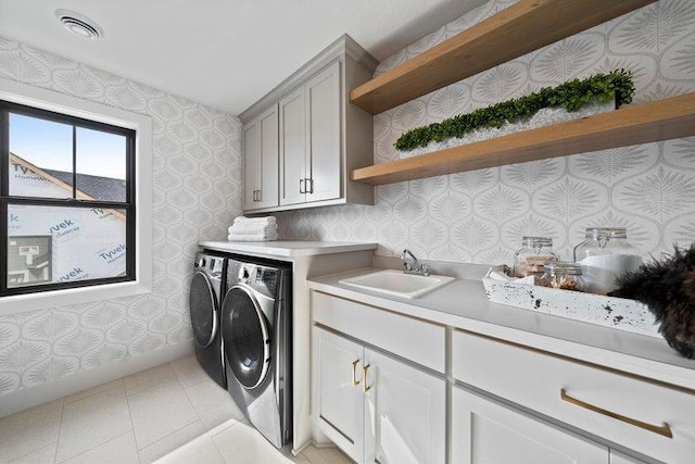 clothes washing area with cabinets, light tile patterned flooring, sink, and washing machine and dryer