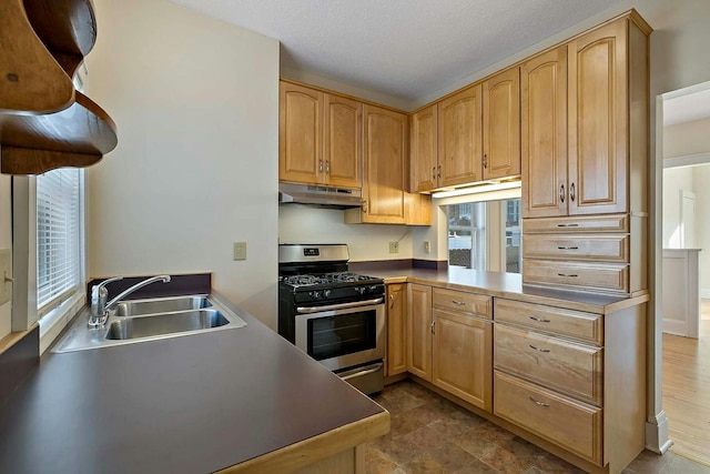 kitchen featuring a textured ceiling, sink, stainless steel gas stove, and light brown cabinetry