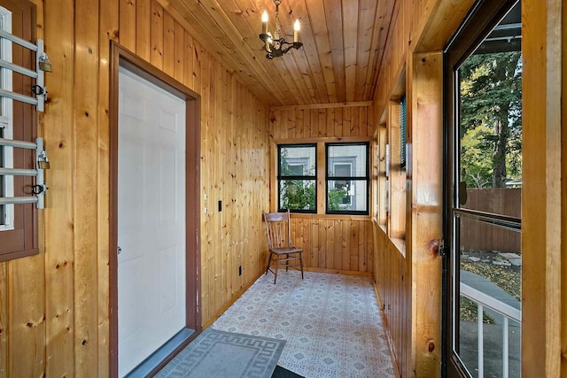 unfurnished sunroom featuring a healthy amount of sunlight, wooden ceiling, and a chandelier