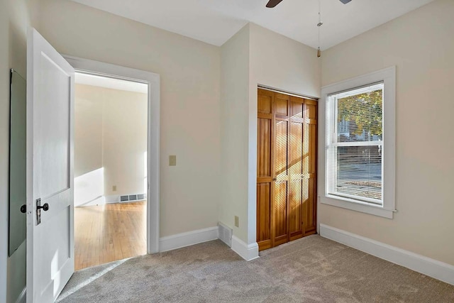 unfurnished bedroom with light carpet, a closet, and ceiling fan