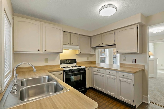 kitchen with kitchen peninsula, white cabinets, a textured ceiling, black range with gas cooktop, and sink