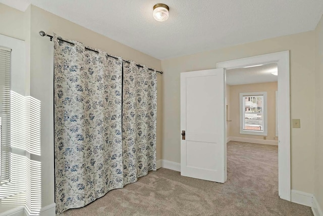 unfurnished bedroom featuring a textured ceiling and light colored carpet