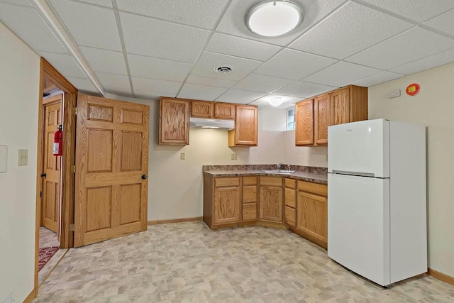 kitchen featuring a paneled ceiling, sink, and white refrigerator