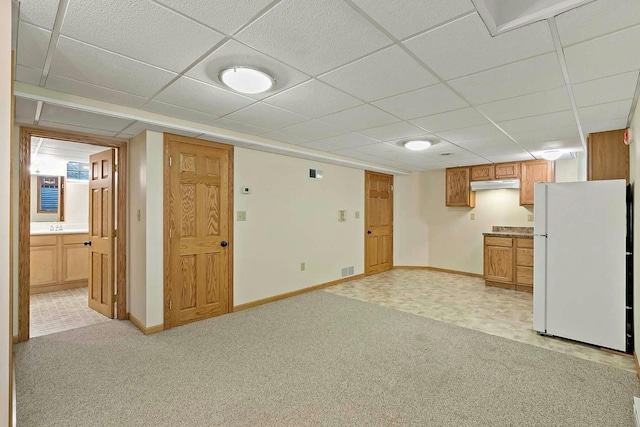 interior space with a drop ceiling and white refrigerator