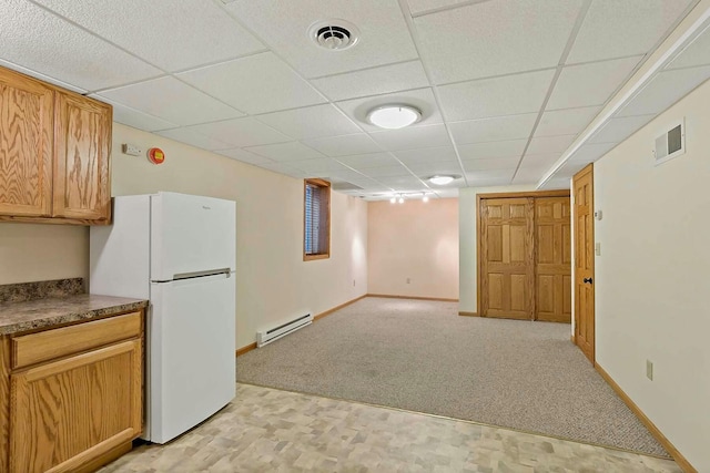 kitchen with baseboard heating, white fridge, light colored carpet, and a paneled ceiling