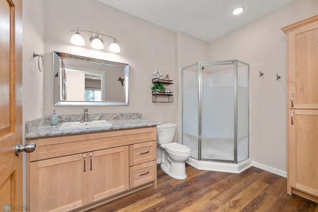 bathroom with vanity, hardwood / wood-style floors, a shower with shower door, and toilet