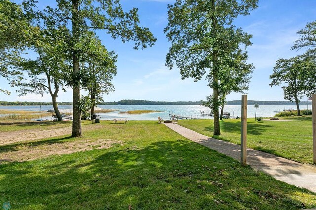 surrounding community with a water view and a lawn