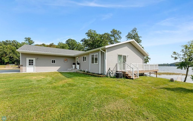 back of property featuring a deck with water view, central AC, and a lawn