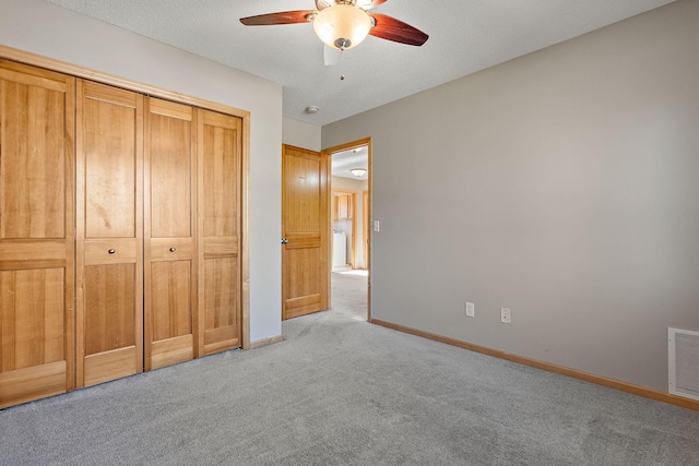 unfurnished bedroom featuring ceiling fan, a textured ceiling, a closet, and light colored carpet