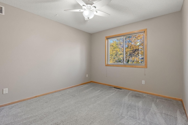 carpeted spare room with a textured ceiling and ceiling fan