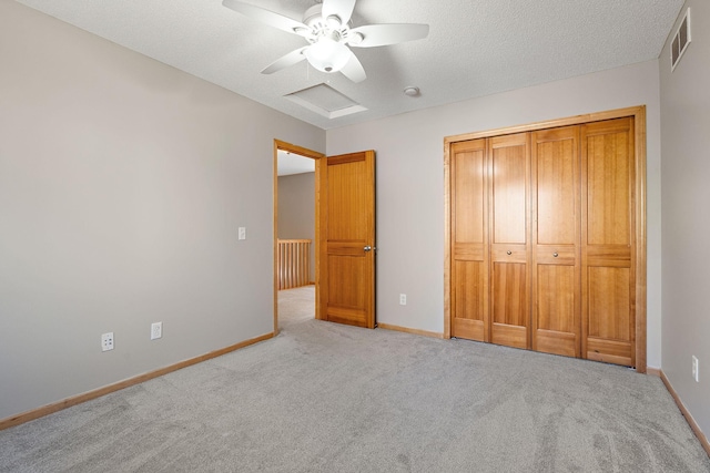 unfurnished bedroom featuring a closet, a textured ceiling, light colored carpet, and ceiling fan