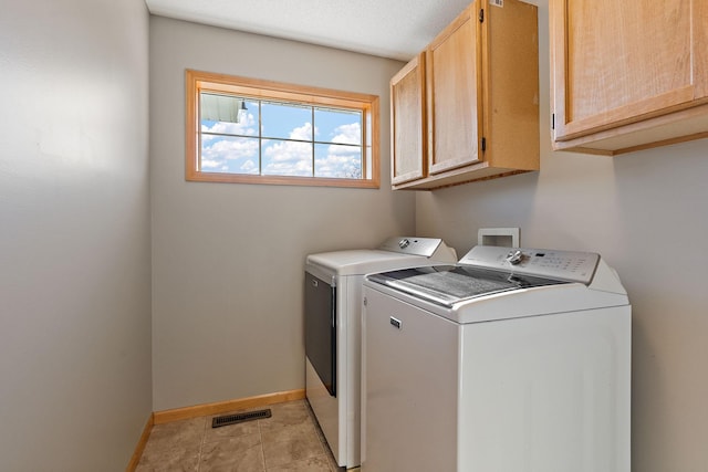 laundry room featuring cabinets, a textured ceiling, washer and dryer, and light tile patterned floors