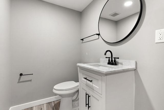 bathroom with toilet, vanity, and hardwood / wood-style floors