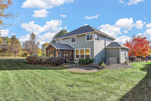 rear view of property featuring a lawn and a sunroom