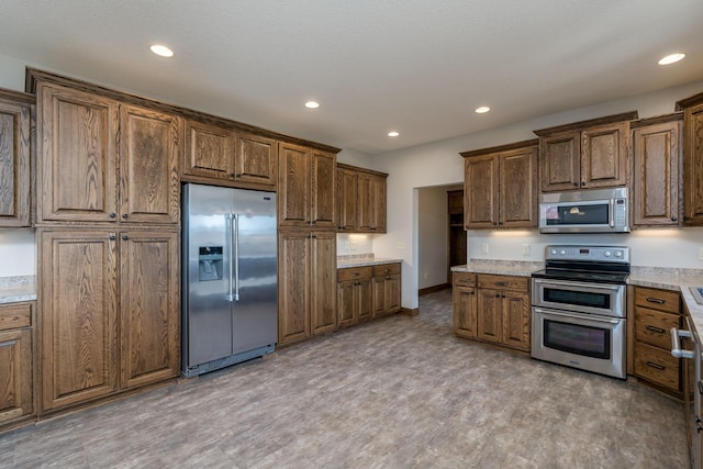 kitchen featuring hardwood / wood-style flooring, stainless steel appliances, and light stone countertops