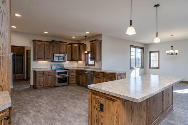 kitchen featuring a kitchen breakfast bar, sink, pendant lighting, an inviting chandelier, and appliances with stainless steel finishes