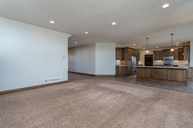 kitchen featuring appliances with stainless steel finishes, a textured ceiling, a center island, pendant lighting, and dark colored carpet