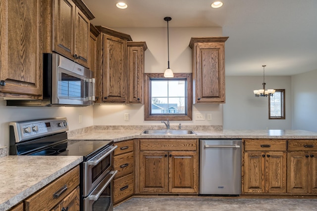 kitchen with kitchen peninsula, sink, pendant lighting, a notable chandelier, and stainless steel appliances