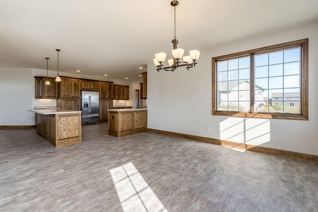 kitchen featuring a kitchen island, kitchen peninsula, stainless steel fridge, decorative light fixtures, and a notable chandelier