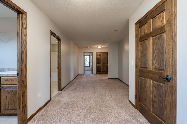 hall featuring a textured ceiling and light colored carpet