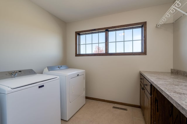 washroom featuring washer and dryer, light tile patterned flooring, and cabinets