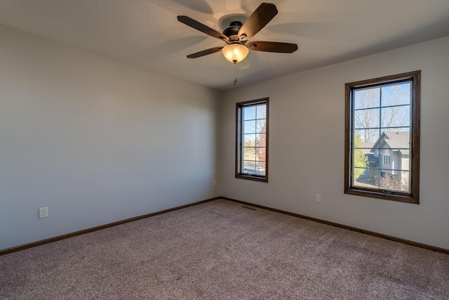 unfurnished room featuring ceiling fan, carpet flooring, and a wealth of natural light