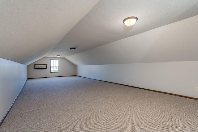 bonus room featuring lofted ceiling, a wall mounted AC, light carpet, and a textured ceiling