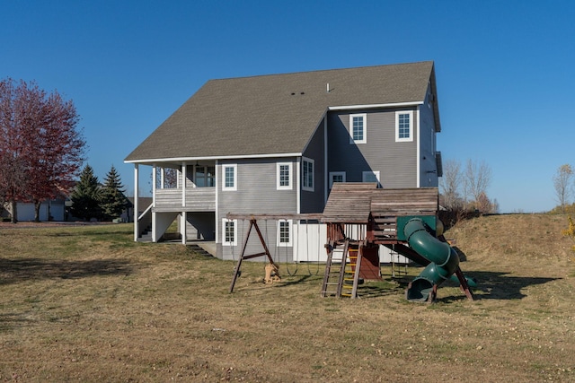 rear view of house with a yard and a playground