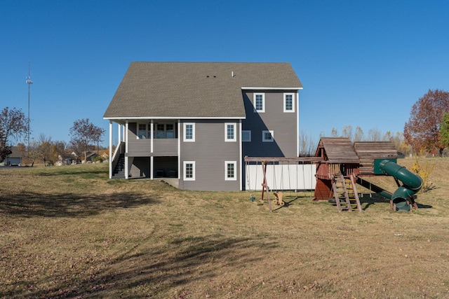 back of property with a lawn and a playground