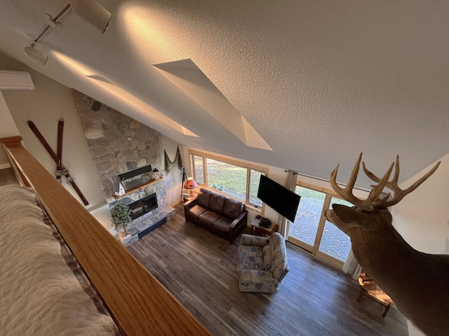 8291 Boy Lake Dr NE, Remer, MN 56672 - living area with wood finished floors, a stone fireplace, rail lighting, a textured ceiling, and vaulted ceiling