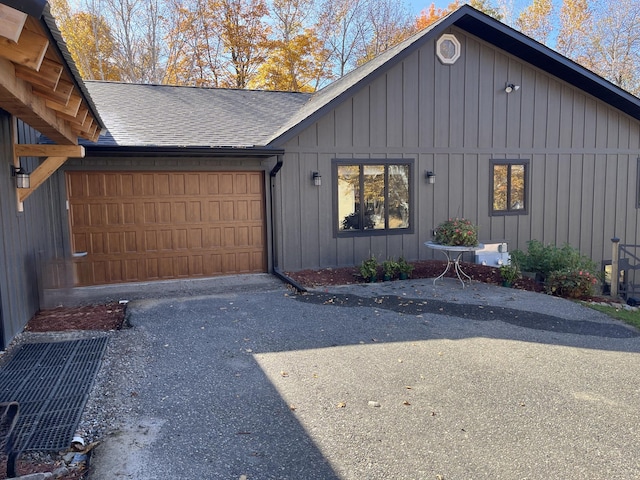 8291 Boy Lake Dr NE, Remer, MN 56672 - view of side of property featuring board and batten siding, an attached garage, roof with shingles, and asphalt driveway