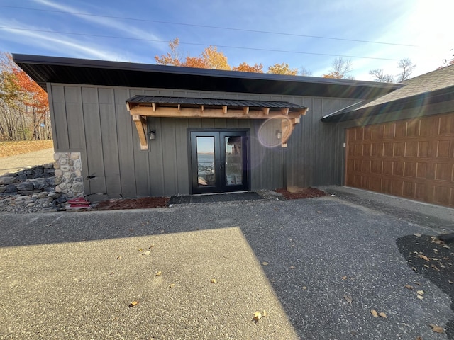 8291 Boy Lake Dr NE, Remer, MN 56672 - property entrance with board and batten siding, an attached garage, asphalt driveway, and french doors