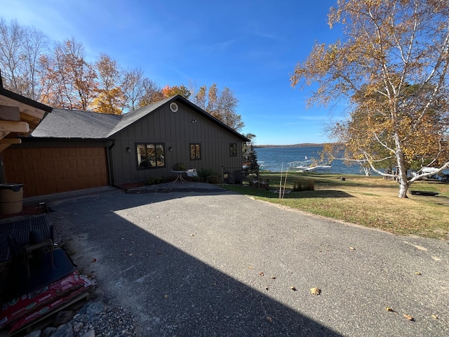 8291 Boy Lake Dr NE, Remer, MN 56672 - view of front facade with board and batten siding, an attached garage, a water view, driveway, and a front yard
