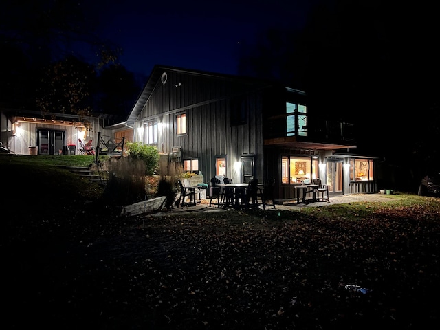 8291 Boy Lake Dr NE, Remer, MN 56672 - back of house at night featuring board and batten siding and a patio