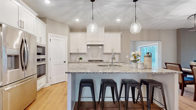 kitchen with stainless steel appliances, pendant lighting, and white cabinets