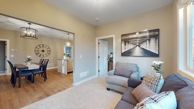 carpeted living room featuring a chandelier and a textured ceiling