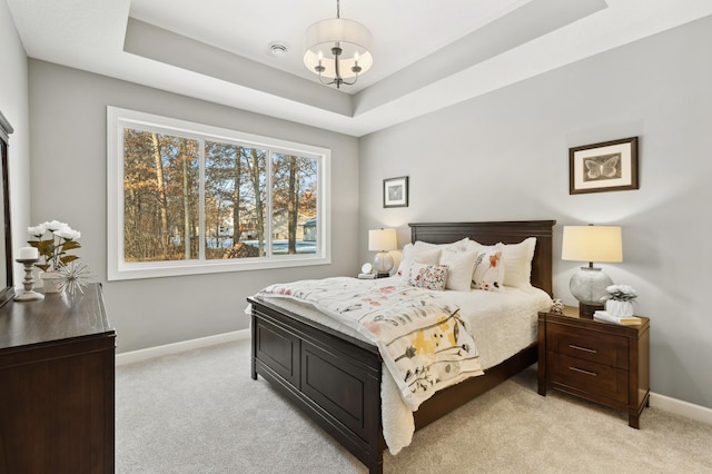 carpeted bedroom featuring a notable chandelier and a raised ceiling