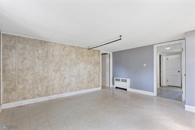 unfurnished room with wood walls and radiator heating unit