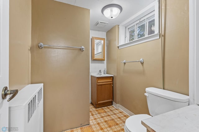 bathroom featuring vanity, toilet, and radiator