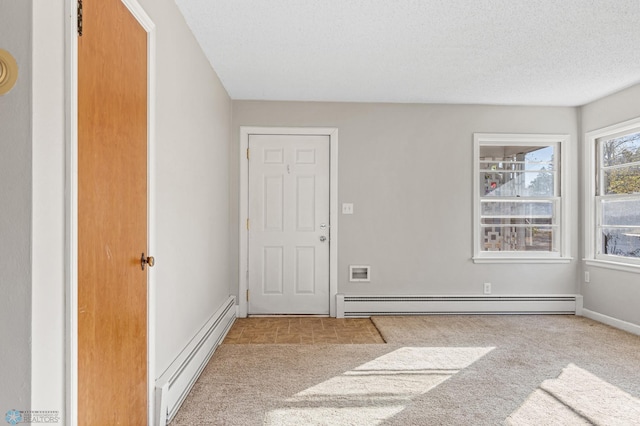 carpeted spare room with a baseboard radiator and a textured ceiling