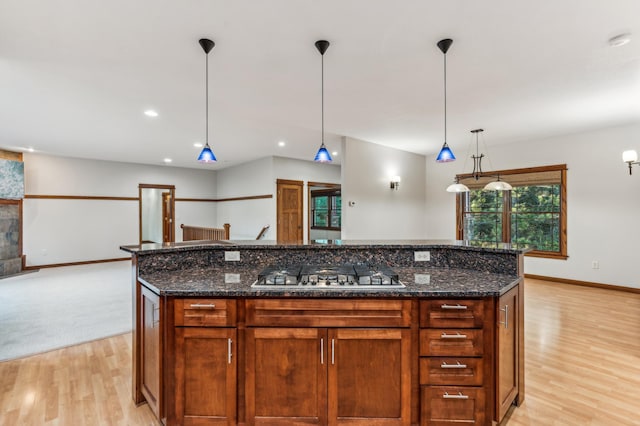 kitchen with a kitchen island, stainless steel gas cooktop, light hardwood / wood-style floors, and hanging light fixtures