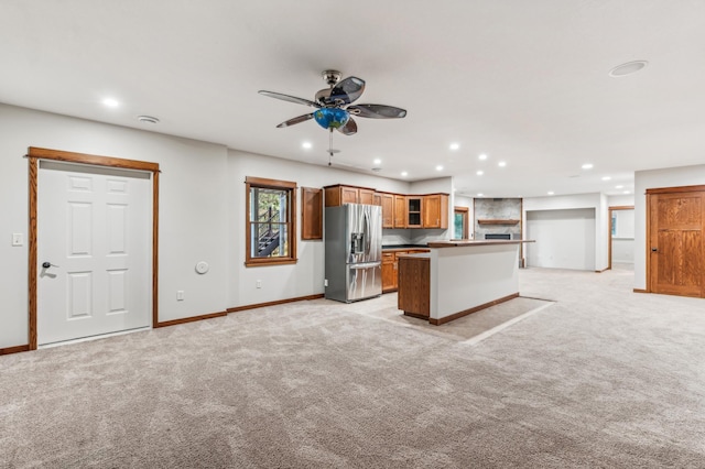 kitchen featuring ceiling fan, light colored carpet, stainless steel fridge, and a center island