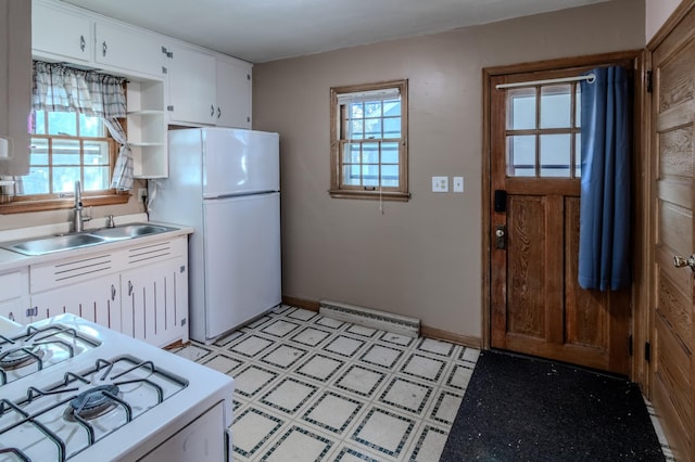 kitchen with white cabinets, a wealth of natural light, sink, and white appliances