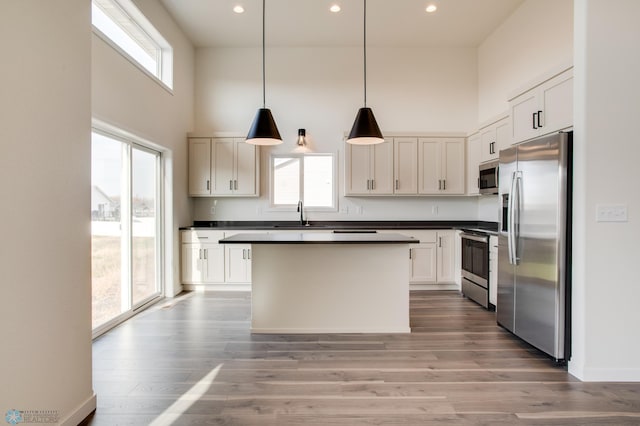 kitchen with a healthy amount of sunlight, white cabinets, stainless steel appliances, and hanging light fixtures