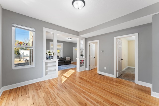 spare room featuring light hardwood / wood-style flooring and ornate columns